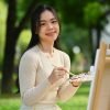 pretty-young-asian-woman-enjoying-painting-picture-2024-11-27-11-21-30-utc Pretty young Asian woman enjoying painting picture in green park on beautiful day